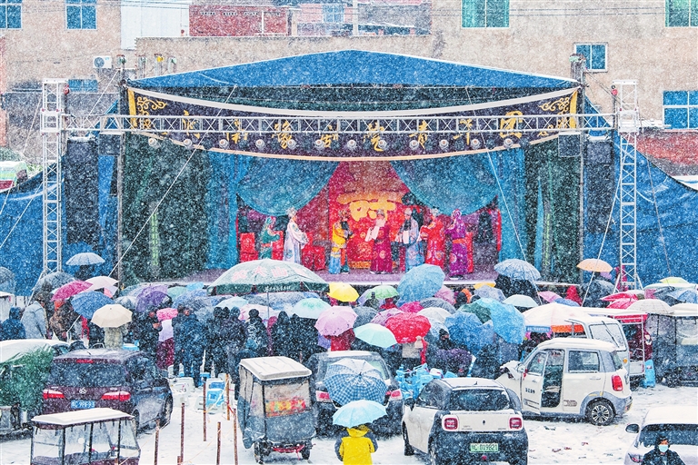大雪中，观众撑着伞守在戏台前 一台戏，“暖”了寒冬